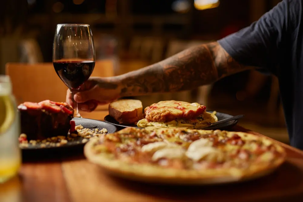 Brindis con vino sobre pizza y pasta